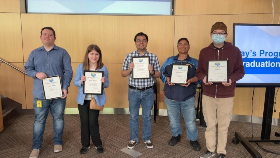 5 graduates stand with certificates