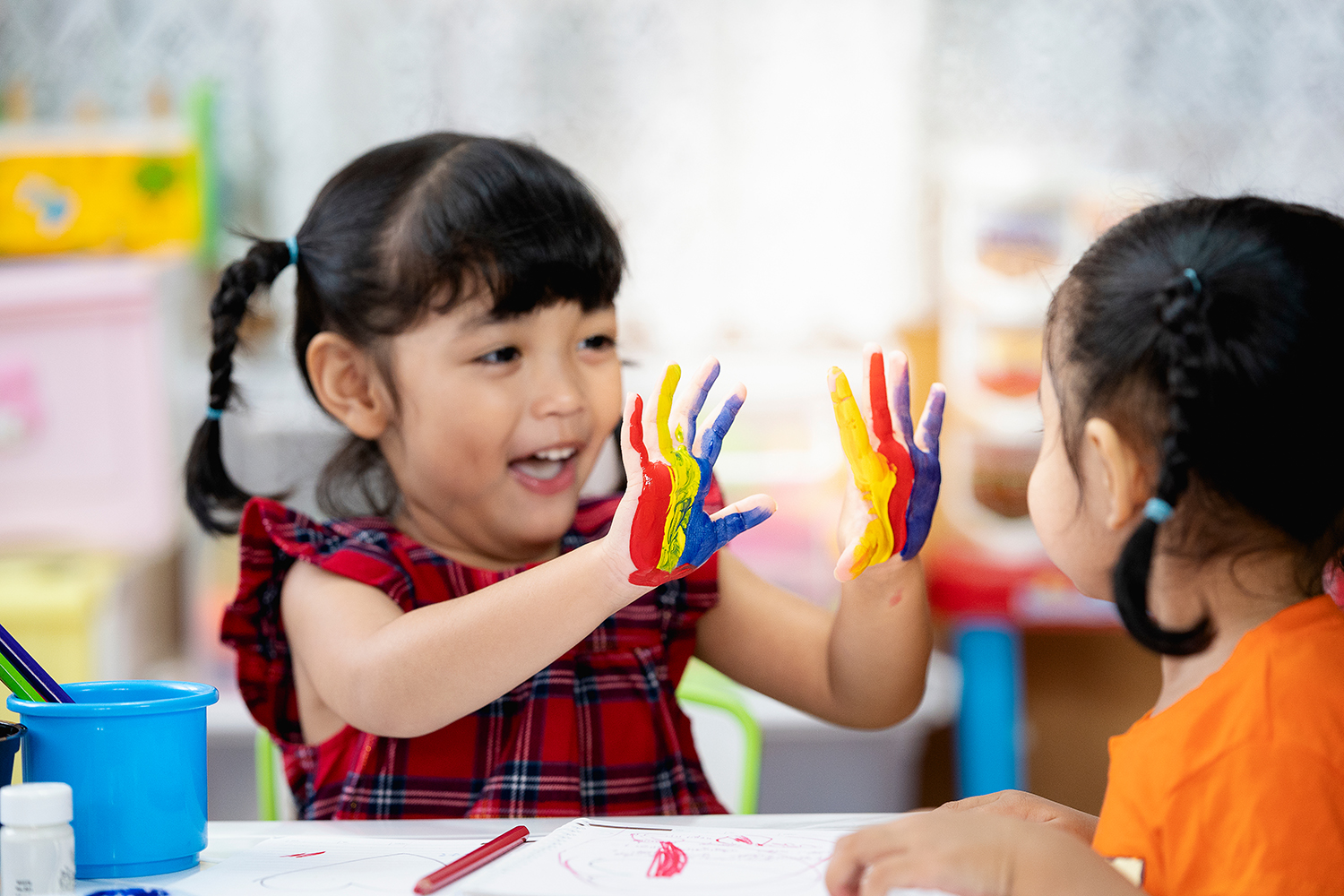 Pre-school girl shows painted hands to another girl.