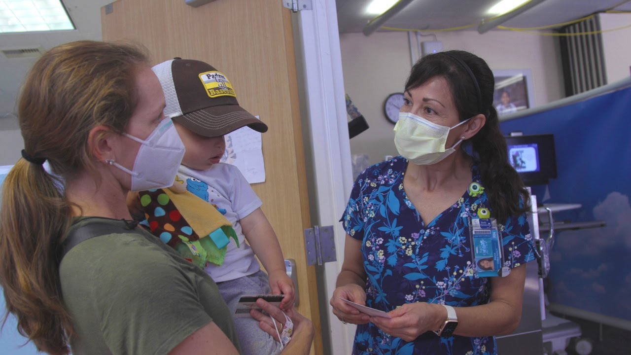 woman holds child and stands with medical professional