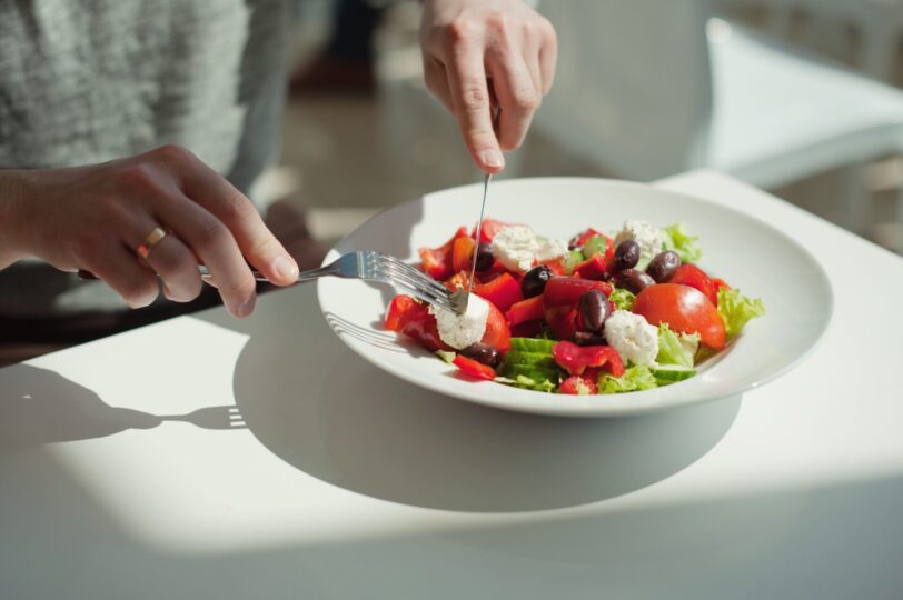 Close up on a person's hands cutting into a salad