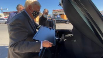 Supervisor Greg Cox places a computer into the truck of a car