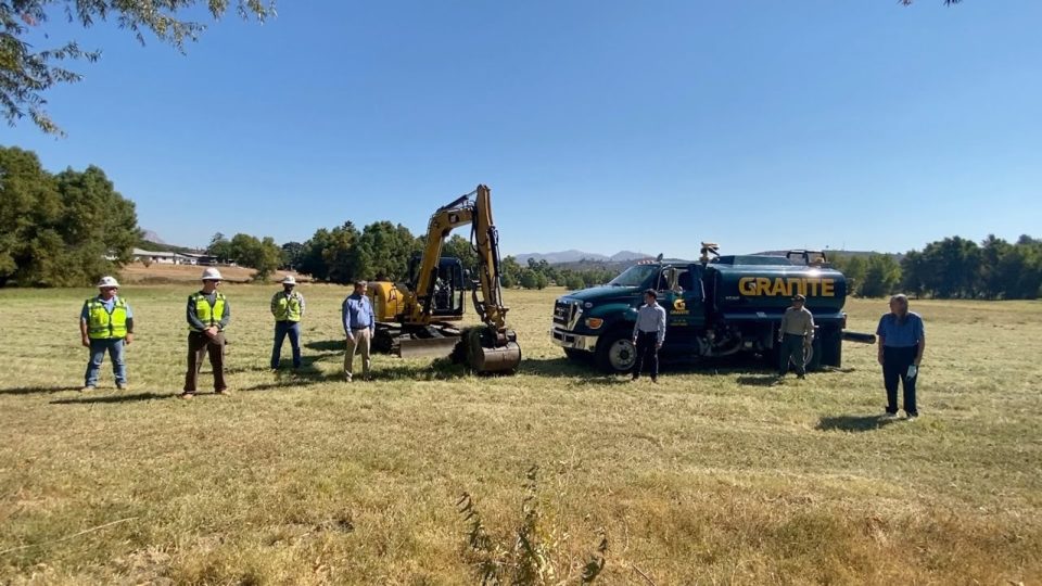 construction workers in a field with a backhoe