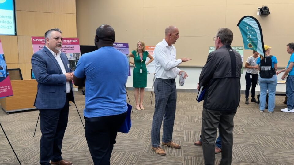 people chat at open house with many displays around the room