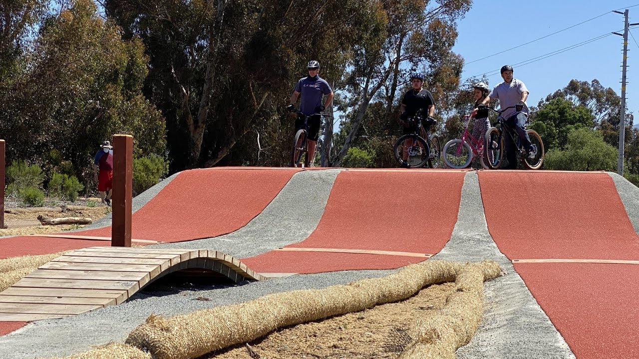 four people on bicycles wait to ride on the pump track