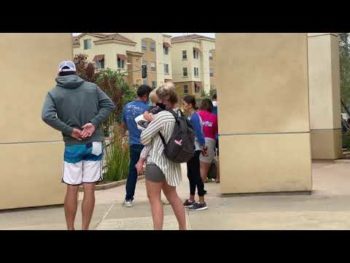 people stand in line outside a COVID-19 testing site
