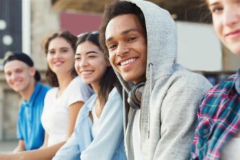 5 teens sit in a line all smiling