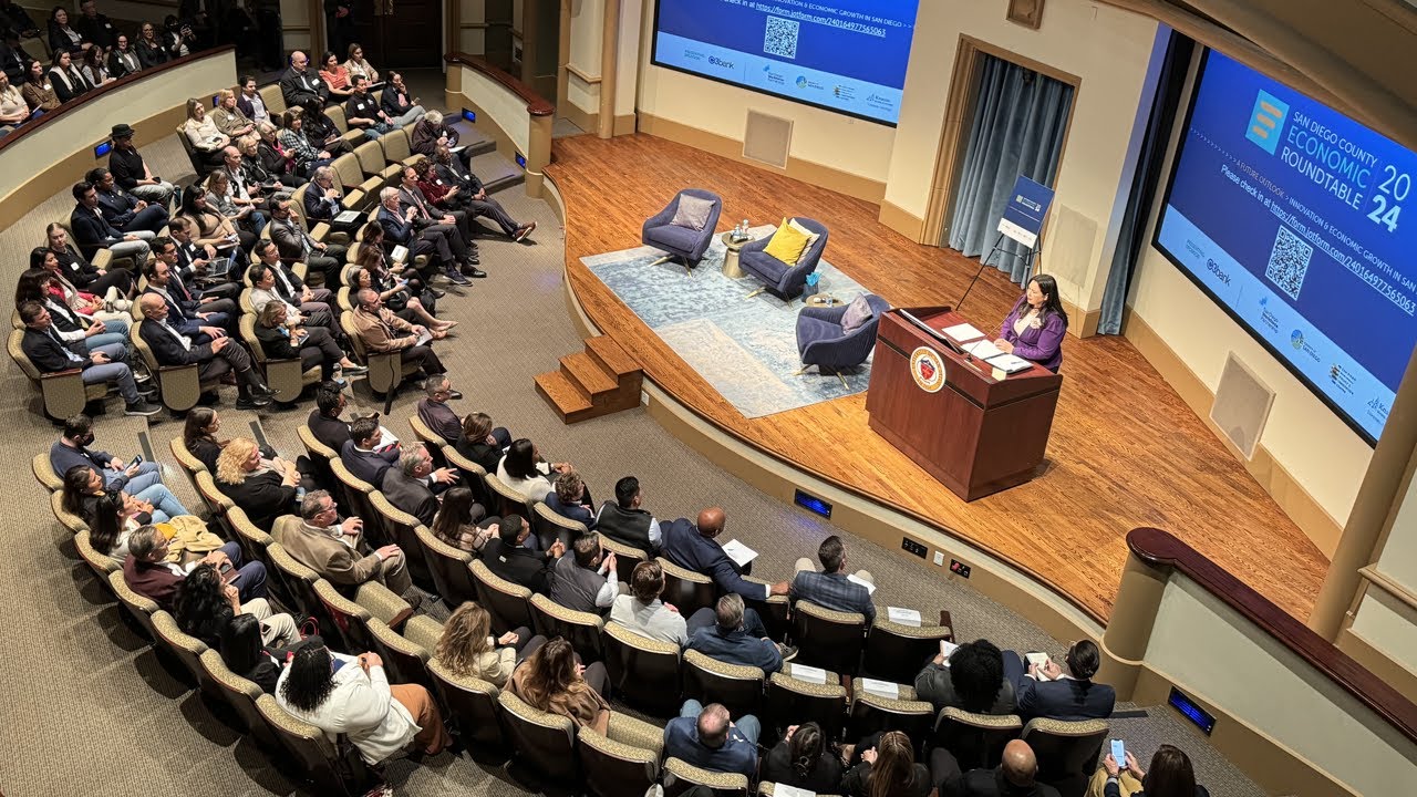 people sit in audience as Nora Vargas stands on stage