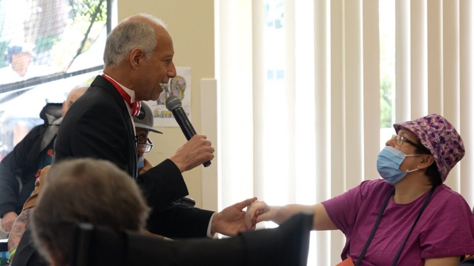 person holding microphone reaches out to hold hand of person