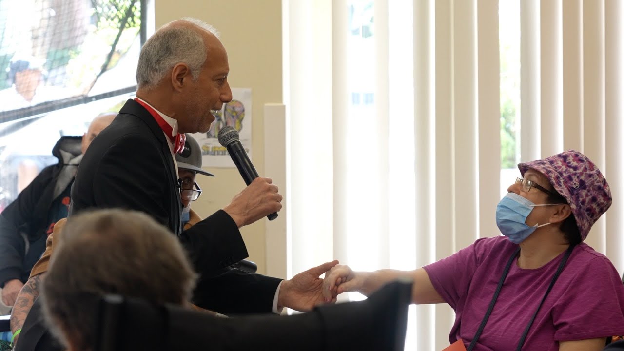 person holding microphone reaches out to hold hand of person