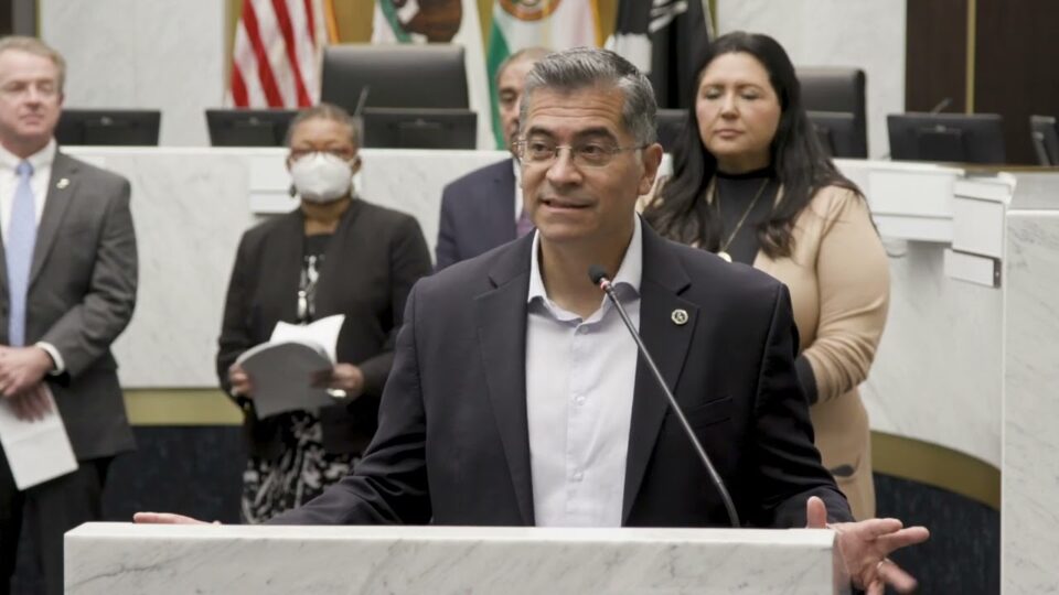Xavier Becerra at podium with people behind him