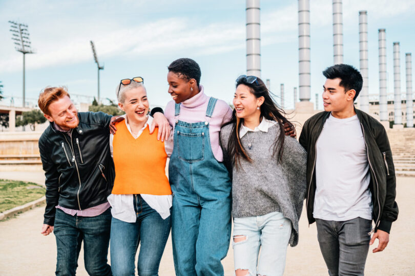 five young adult friends meeting, hugging