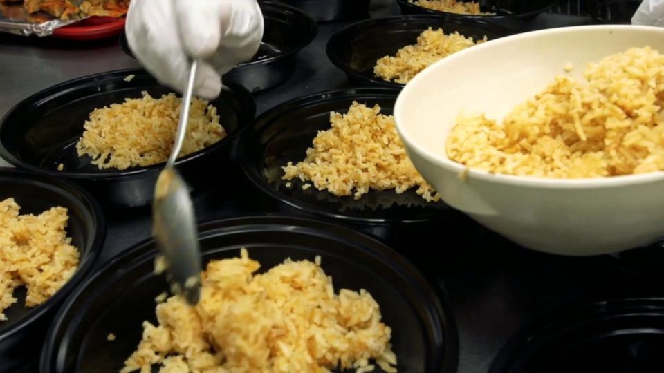 a gloved hand is plating rice