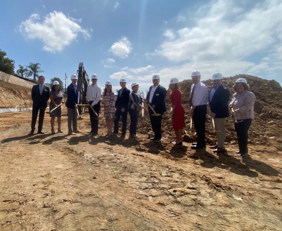 a large group wearing hard hats and holding shovels
