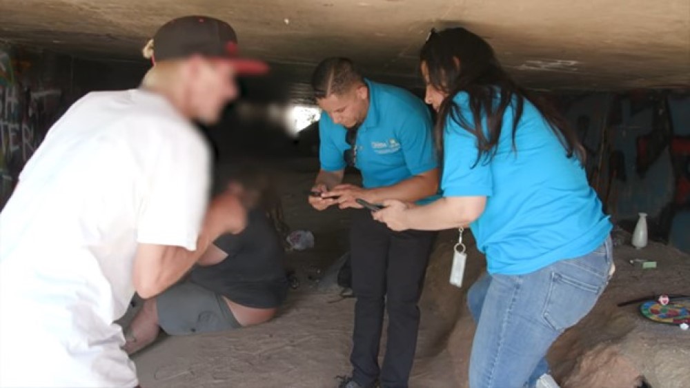 two workers assisting a man