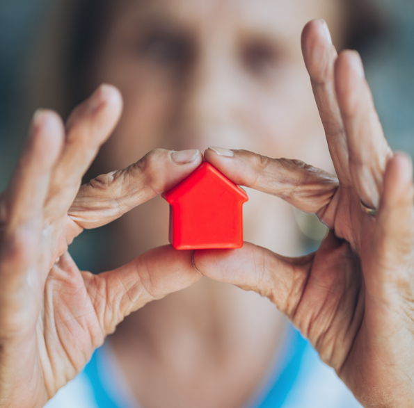 Older woman holding a tiny red toy house.