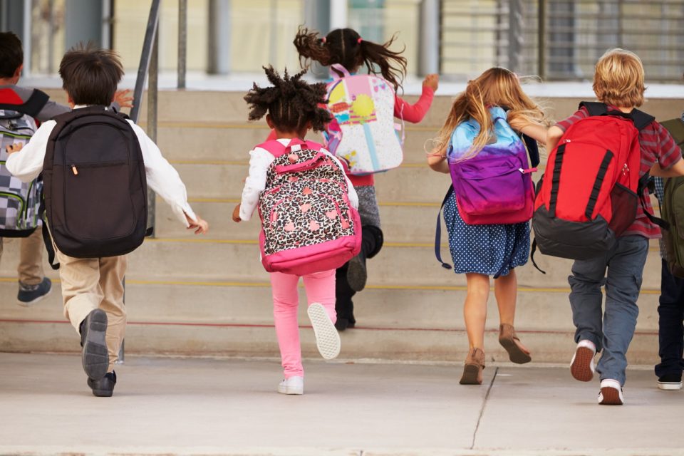 children wearing backpacks and running