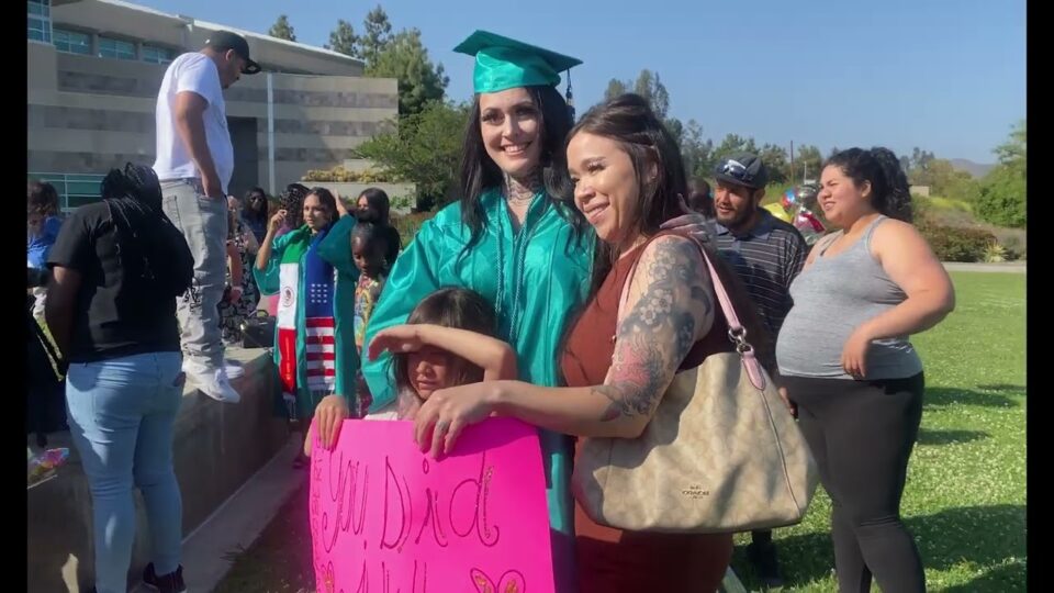 a graduate poses with two people