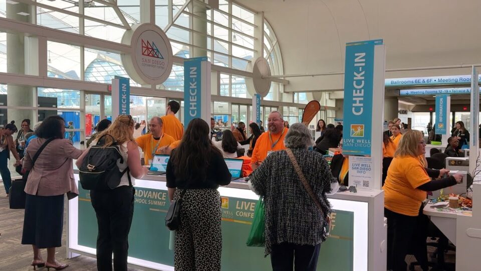 people stand at busy check-in desk at Convention Center