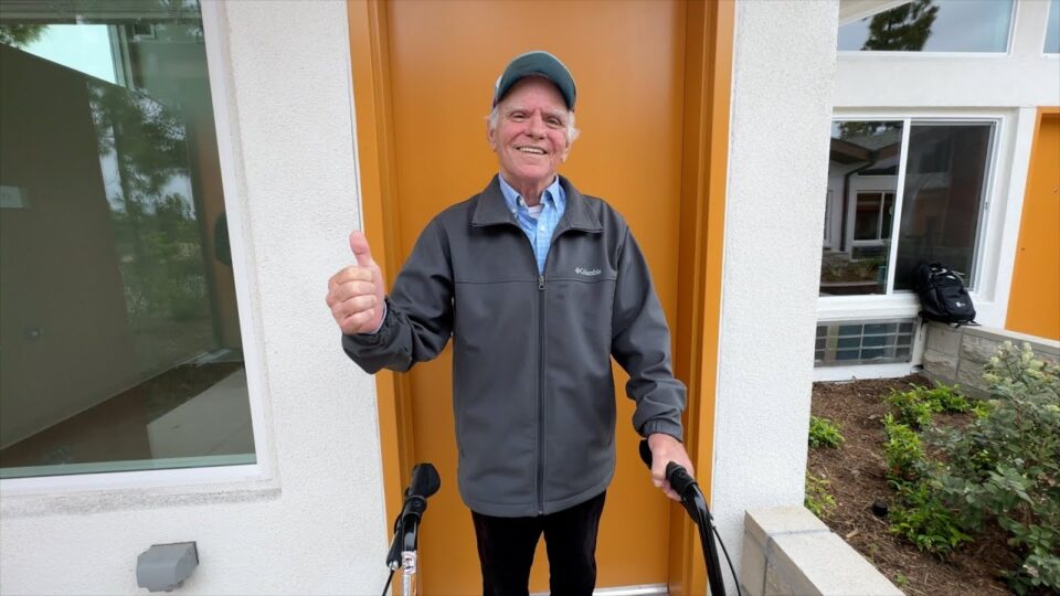 man stands in front of door with thumb up