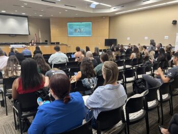 people in a meeting room listening to speaker