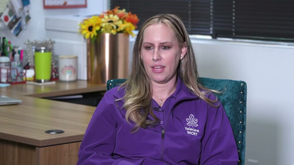 person in purple shirt sits in office