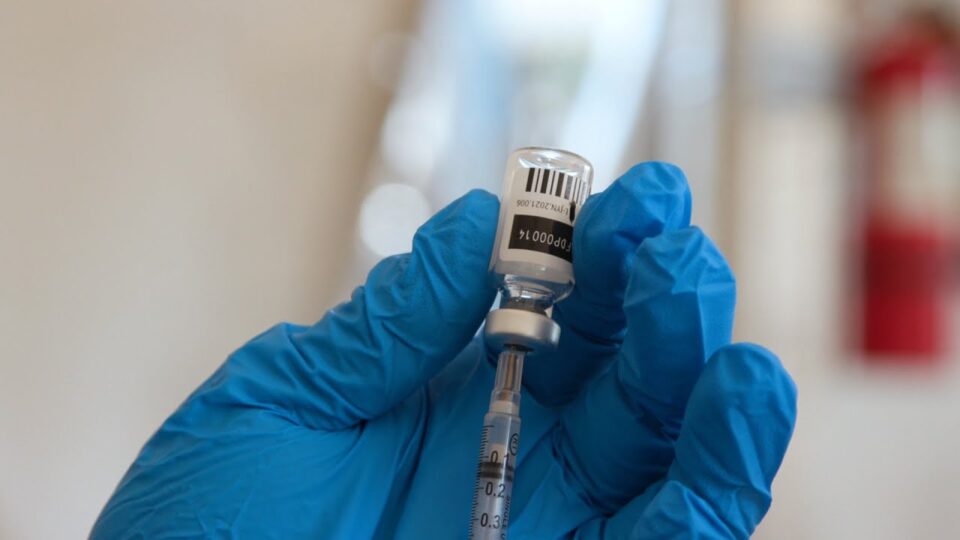 a gloved hand fills a syringe