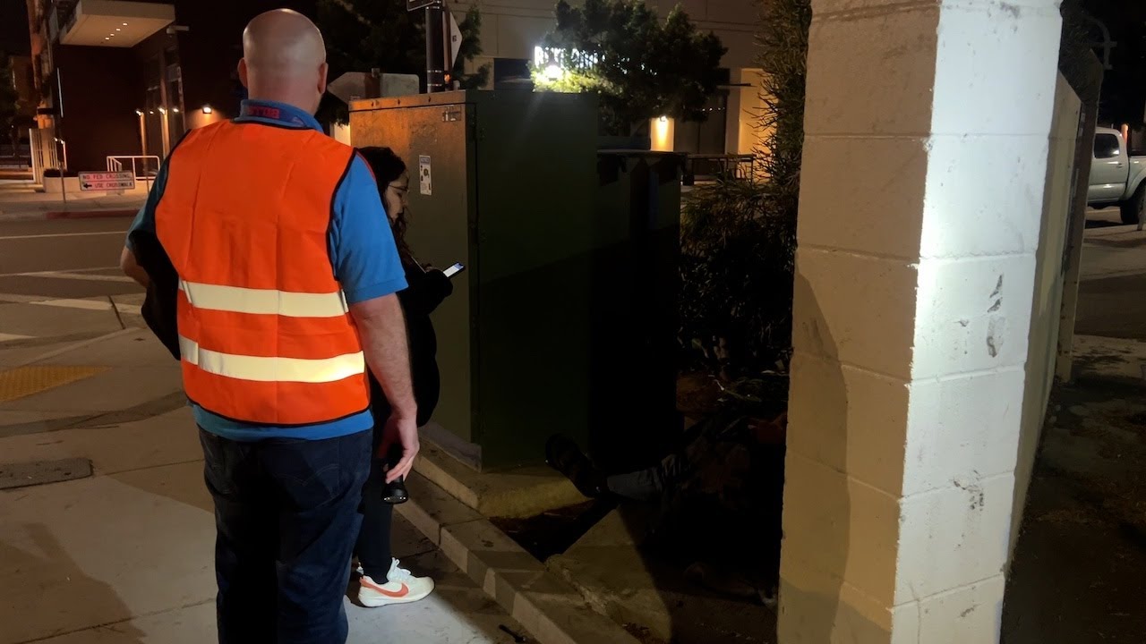 two people stand on sidewalk at night