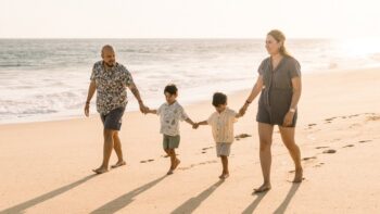family holds hands and walk on beach