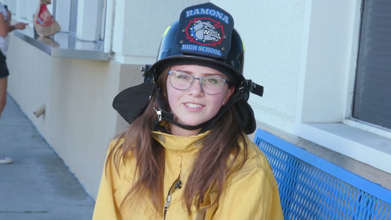 young person wearing firefighting helmet with "Ramona High School" on the front