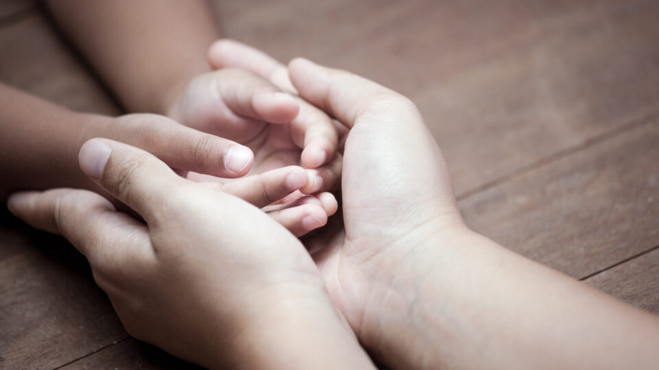Adult holding child's hands