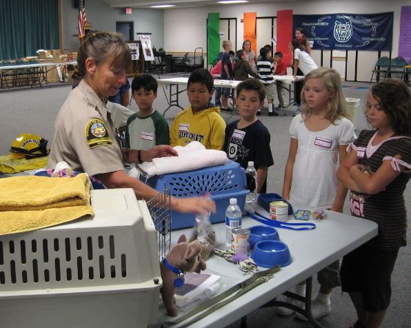 Animal Services officer showing children how to prepare pets for an evacuation.