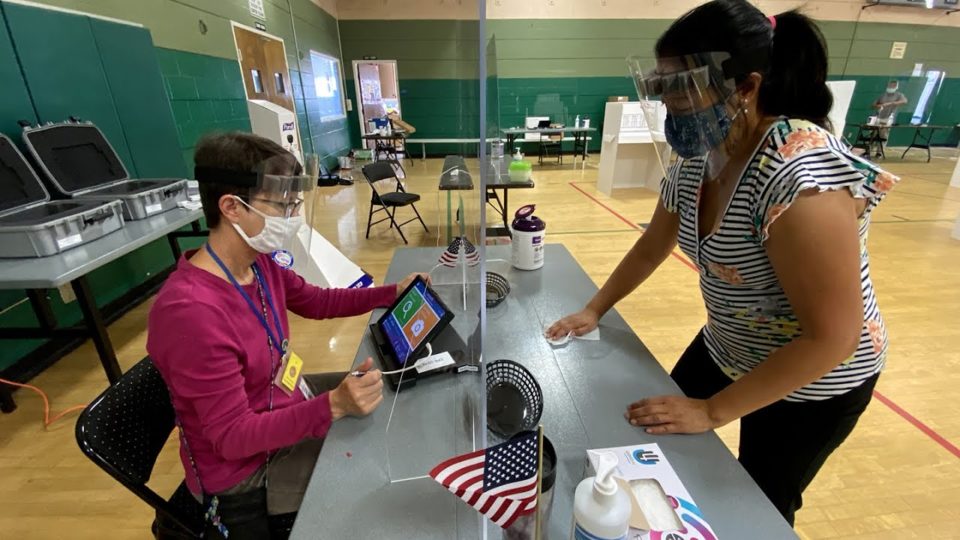 poll workers with masks and face shields keep a polling place clean