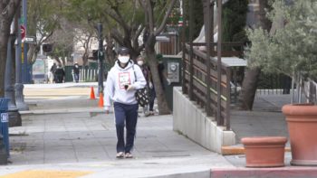 individual walking down the street with a face covering on