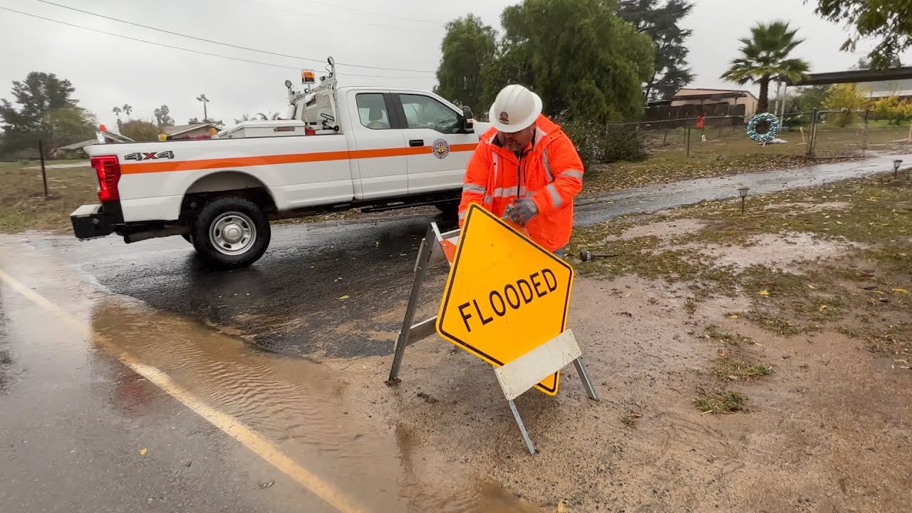 public works employee puts out flooded sign