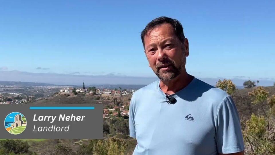 person stands with neighborhood behind him
