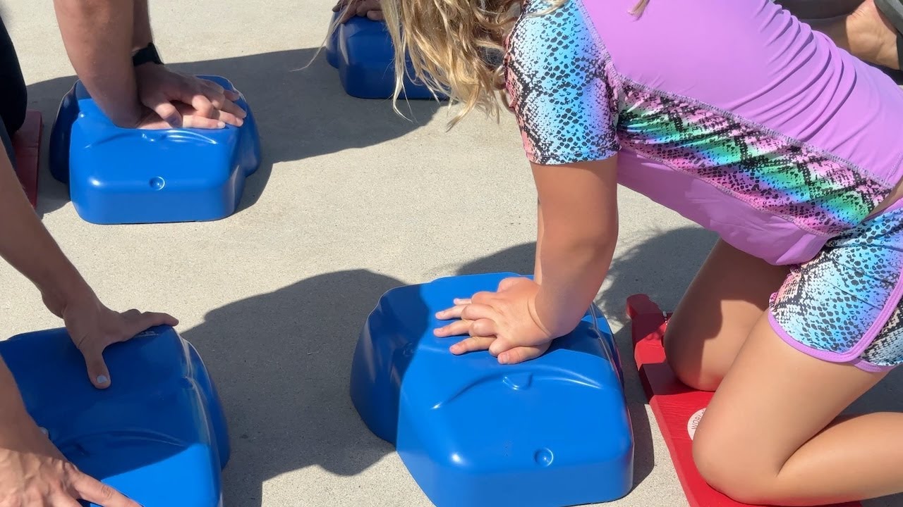 young person practices CPR on torso dummy