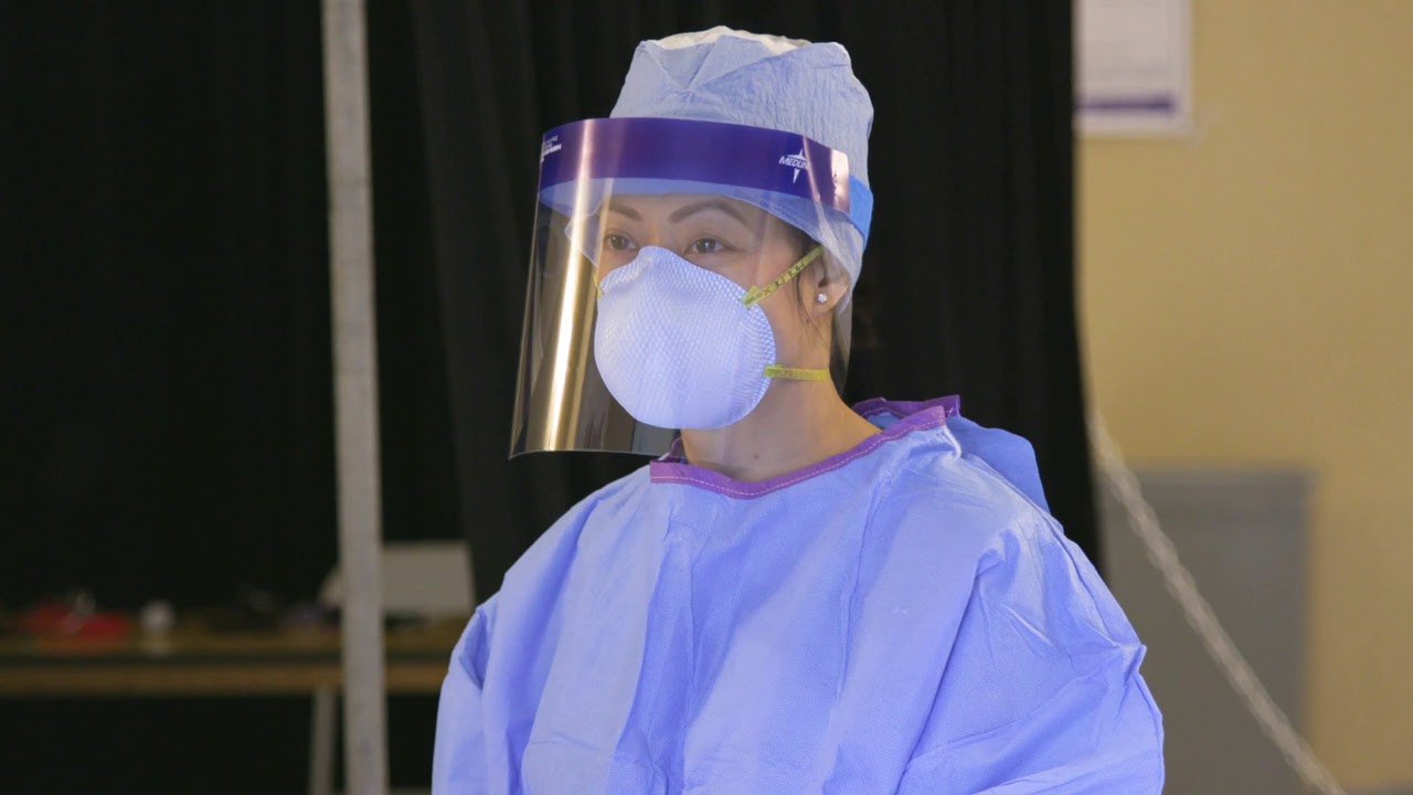 a woman wearing a mask, shield and gown