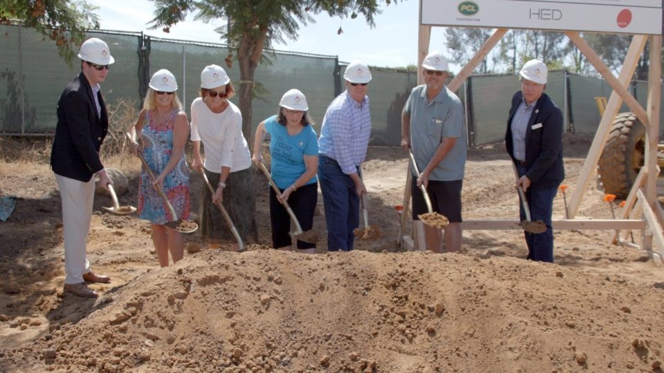 people wearing hard hats shovel dirt
