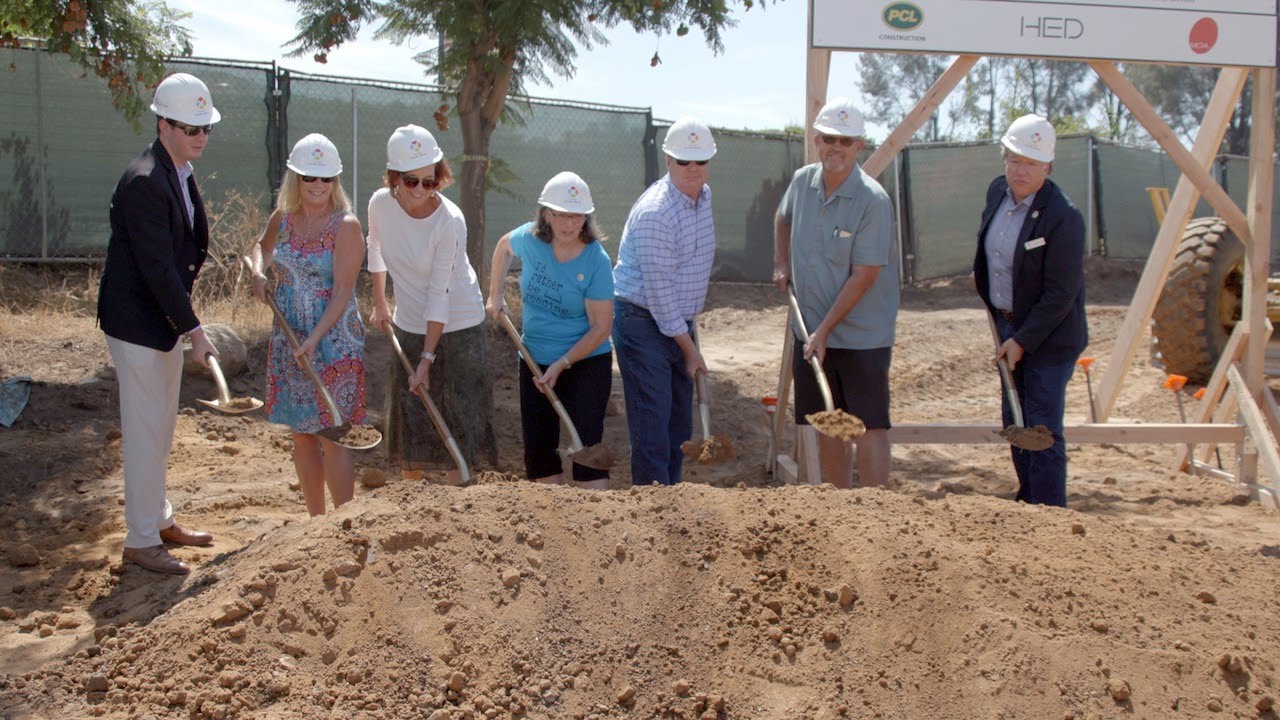 people wearing hard hats shovel dirt
