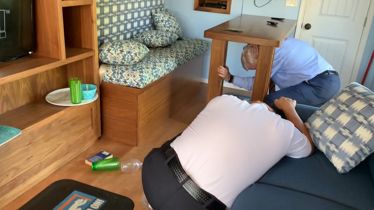 two people drop, cover and hold on in a living space