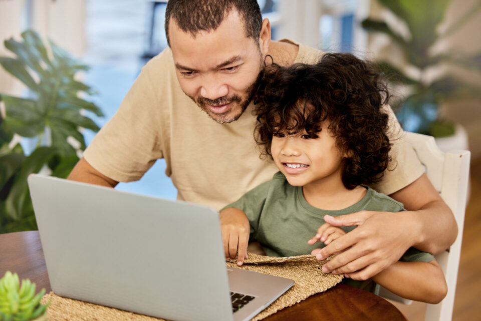 little boy and his father using a laptop together at home.