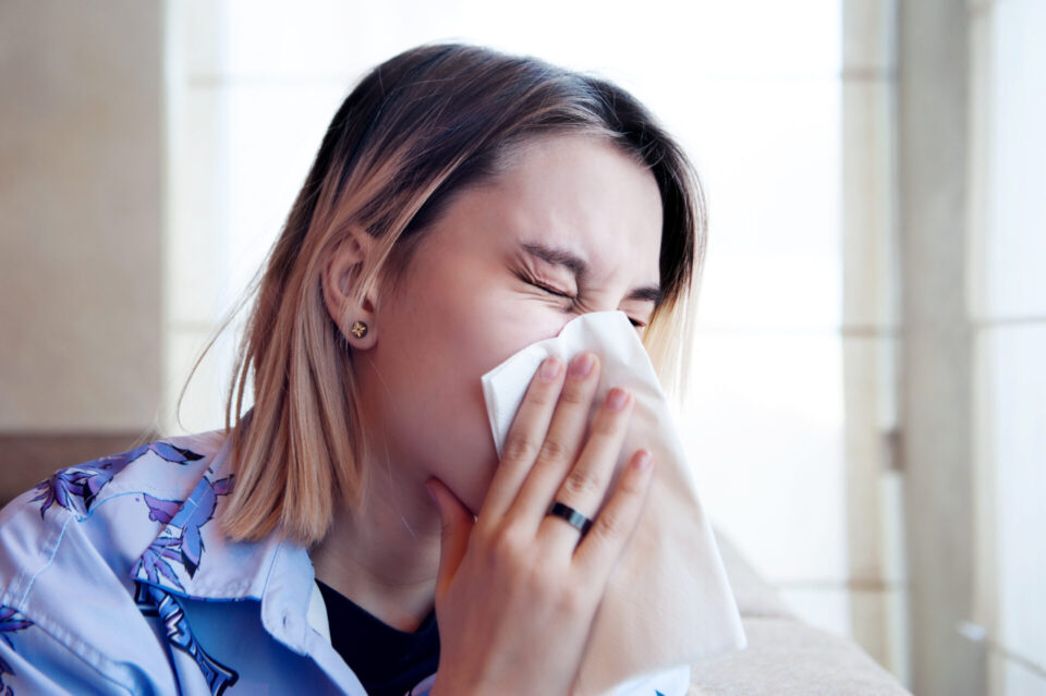 teen sneezing into tissue