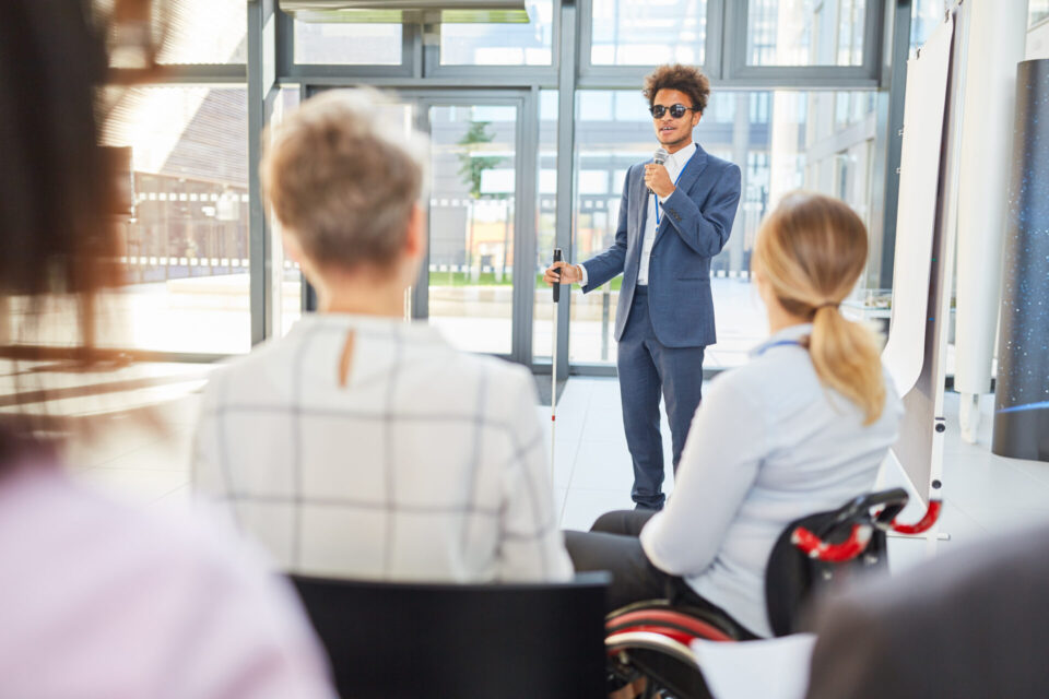 man with white cane speaks to group