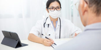 doctor with a mask on speaks to a patient