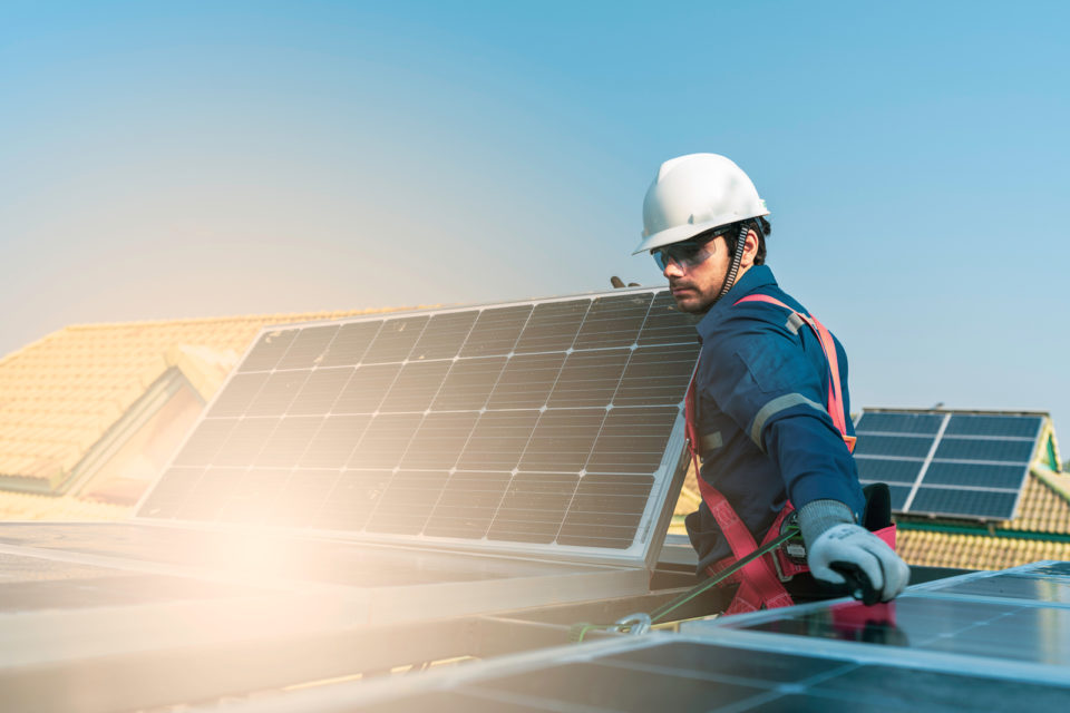 man works on a roof with a solar panel