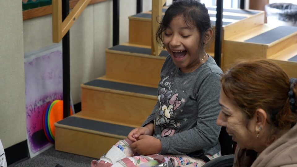 child smiles with adult in PT room