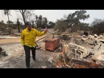 Burned home with man surveying damage.