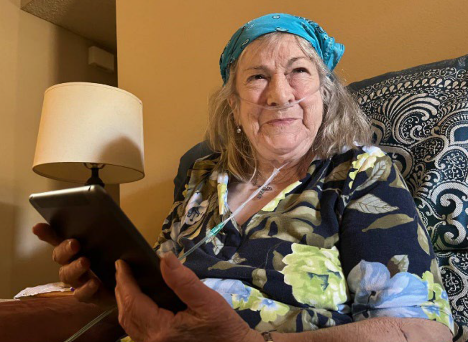 Older adult smiles and hold up tablet