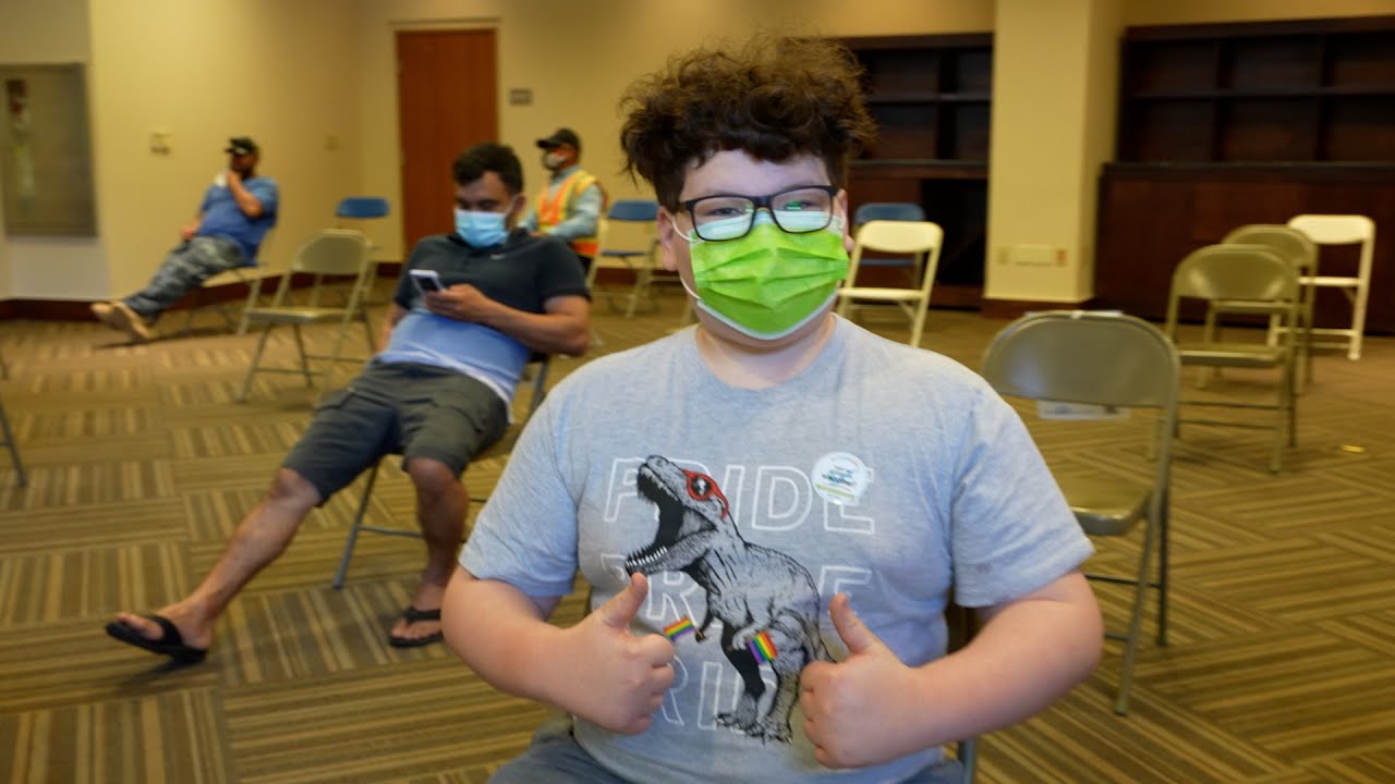 teen with mask on gives two thumbs up after a vaccine