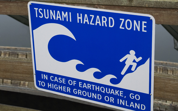 Sign that reads Tsunami Hazard Zone advising people to move away from water